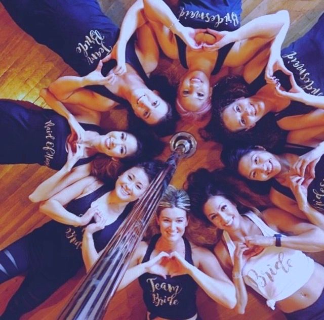 Bachelorette group lying in a circle around a pole, smiling up at the camera