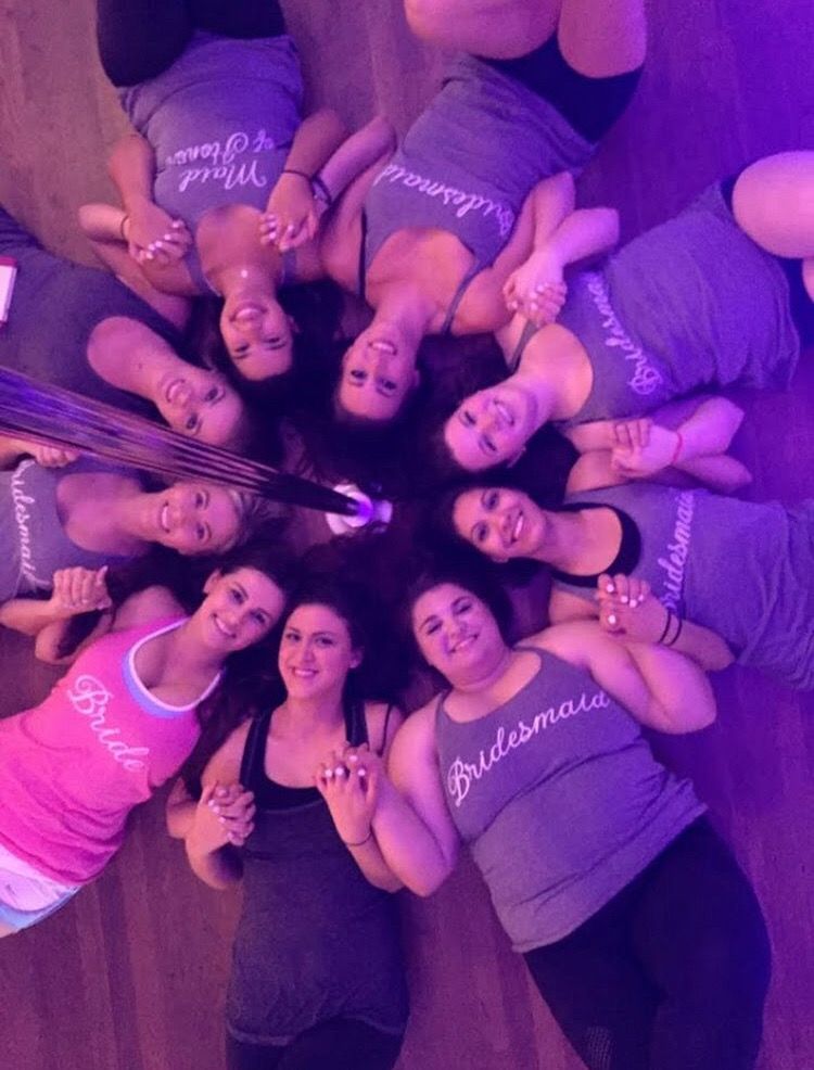 Party group in a circle under purple light, smiling up