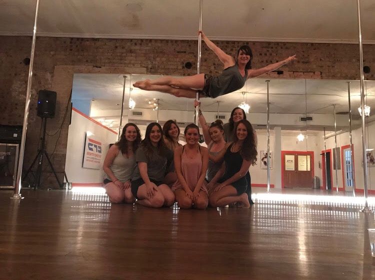 Class group kneeling in the studio while an aerialist performs above them