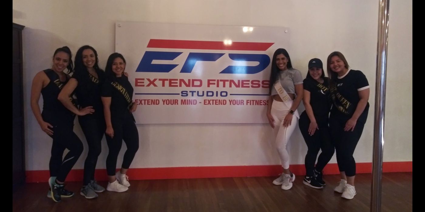 Students standing in front of the Extend Fitness Studio wall sign